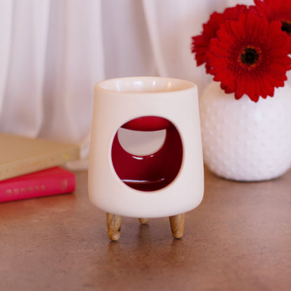 Ceramic wax warmer essential oil warmer by Arya Tara Candles. White outside red inside colored. Ceramic handmade tealight wax warmer with wooden legs.